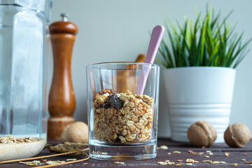 Useful muesli with nuts in a glass and a spoon on a wooden table. Healthy lifestyle