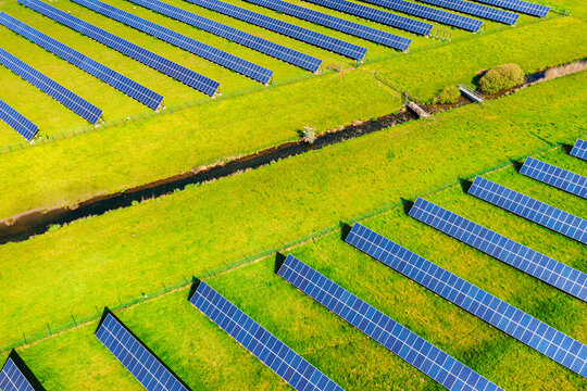 Solar panels of photovoltaic power plant from above with watercourse. Renewable resource of energy
