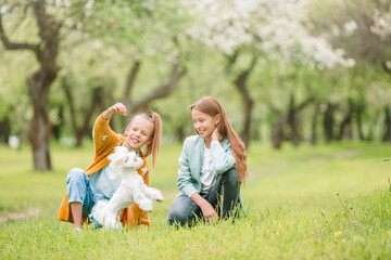 Little smiling girls playing and hugging puppy in the park