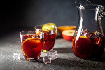 Refreshing red wine sangria or punch with fresh fruits in glasses and pincher on black background