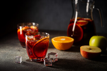 Refreshing red wine sangria or punch with fresh fruits in glasses and pincher on black background
