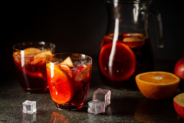 Refreshing red wine sangria or punch with fresh fruits in glasses and pincher on black background