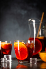 Refreshing red wine sangria or punch with fresh fruits in glasses and pincher on black background