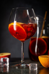 Refreshing red wine sangria or punch with fresh fruits in glasses and pincher on black background