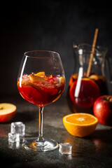 Refreshing red wine sangria or punch with fresh fruits in glasses and pincher on black background