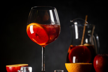 Refreshing red wine sangria or punch with fresh fruits in glasses and pincher on black background
