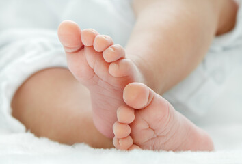 Newborn baby feet on white blanket closeup