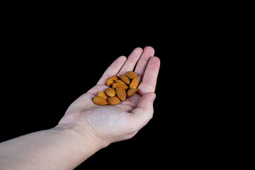 handful of almonds in the palm on a black background