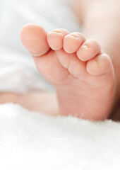 Obraz na płótnie Canvas Newborn's foot on white blanket for your a baby shower card
