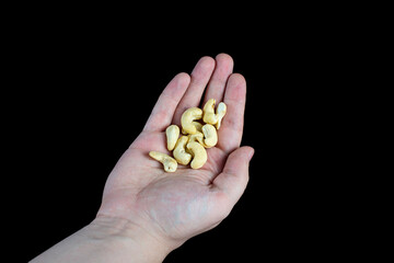 handful of cashews in a palm on a black background