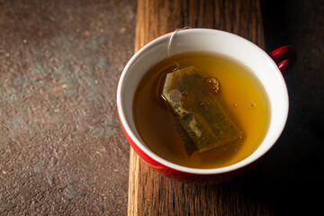 Tea bag in a red cup with hot water, top view