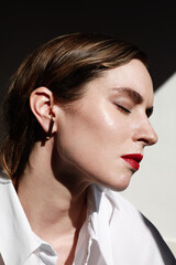 Close-up face of beautiful caucasian brunet woman with red lips and closed eyes. Vertical shot.