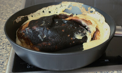 Cooking fail. Burned omelet in pan close-up. Amateur culinary. Chores.	