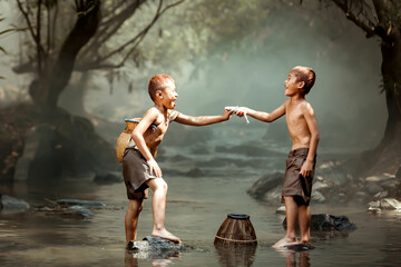 Two boys Fishing in the streams near their home in the countryside of Thailand