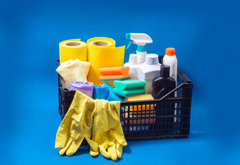 Home cleaning supplies in box on blue background. Indoor cleaning concept