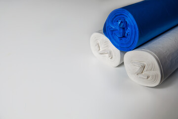 Blue and white plastic trash bags on a white surface. Recyclable materials to protect environment. Cleaning facilities during coronavirus isolation. Empty space for copy. Plastic planet pollution.