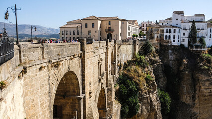 Naklejka na ściany i meble Puente Nuevo famous new bridge in the heart of old village Ronda in Andalusia, Spain. Touristic landmark on a sunny day with buildings in the background. Side angle view.