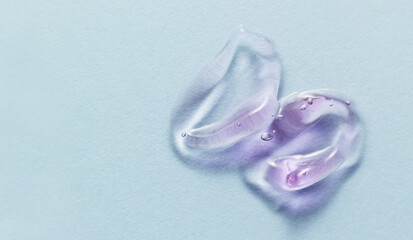 Collagen gel swatch on blue background. Cosmetic serum gel with bubbles smear smudge. Light purple beauty product closeup