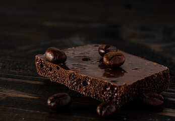 Black porous chocolate with roasted coffee beans on a dark background, coffee shop background, place for text