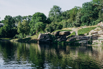 Fototapeta na wymiar Sofia Park, Uman. Beautiful summer park with a lake, tall trees, large stones and statues. Lake with large stones. Lake among the national park