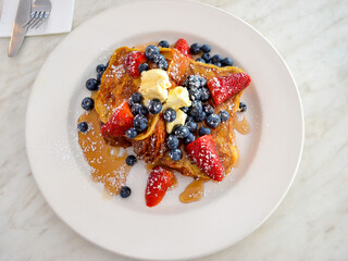 Pain perdu avec du miel, des fraises, des baies et du beurre