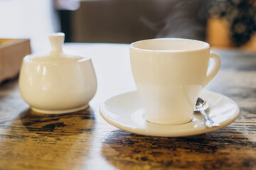 Aromatic fresh coffee in a white cup. Espresso in a small white cup and a sugar bowl in a summer cafe. Fragrant fresh coffee in a restaurant
