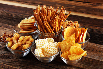 Salty snacks. Pretzels, chips, crackers in glass bowls on table