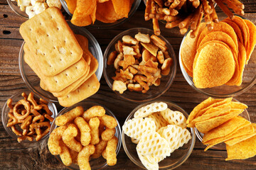 Salty snacks. Pretzels, chips, crackers in glass bowls on table
