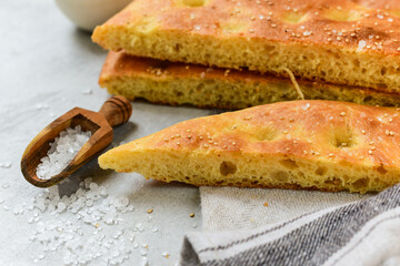 Italian bread focaccia with with sesame and coarse sea salt.  homemade bread recipe. on a grey background, selective focus. top view