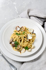 pasta with clams and parsley italian Spaghetti alle Vongole in white plates on a grey background. recipe food seafood.  top view