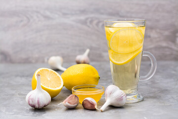 Therapeutic drink of lemon, honey and garlic in a glass on the table. Alternative medicine, treatment with folk remedies.