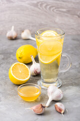 Therapeutic drink of lemon, honey and garlic in a glass on the table. Alternative medicine, treatment with folk remedies.