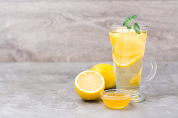 Therapeutic drink of lemon, honey and mint in a glass on the table. Alternative medicine