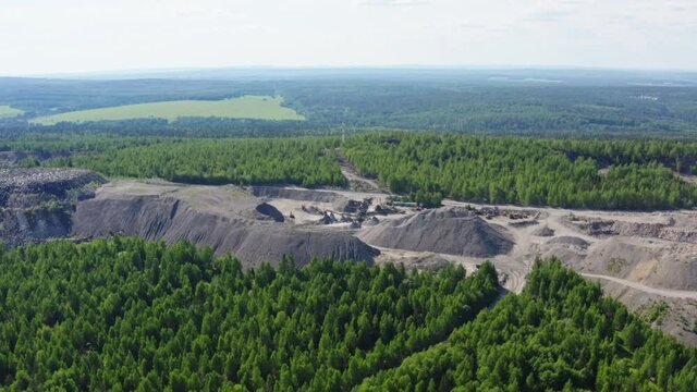 The territory of the quarry for the production of silicates in the middle of green forest. The concept of heavy industry. Aerial view
