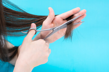 Children's hand cuts the ends of the hair on a blue background. Quarantine Yourself