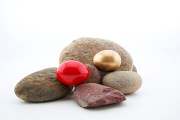 Fototapeta na wymiar Gold egg and red egg placed on rocks with copy space