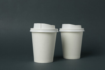 White paper cups on light black background, space for text