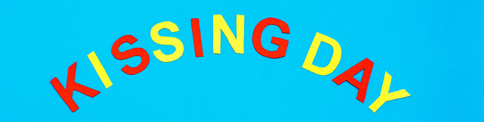 World Kiss Day. Lettering Kissing day made of colored cardboard on a blue background. Web banner