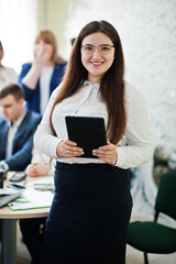 Portrait of caucasian woman in white blouse and eyeglasses hold tablet against business people...