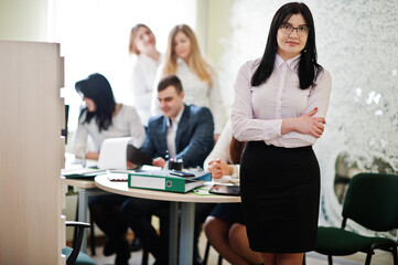 Portrait of caucasian woman in white blouse and eyeglasses against business people group of bank workers have meeting and working in modern office.