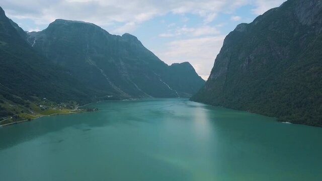 Scenery drone footage of a fjord in Norway with waterfalls on the mountains in the national park of jostedalsbreen