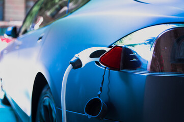 Charging modern electric car with cable plug inserted ir public parking lot