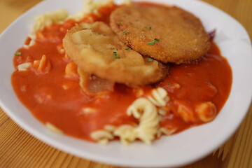 Original German Democratic Republic version of escalope chasseur with breaded Jagdwurst, noodles and tomato sauce                               