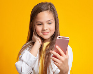 A teenage girl with a smartphone. A beautiful European girl of 10 years old takes a selfie. Cellular communication, gadgets, Internet. Hobbies of teenagers and communication with their peers.