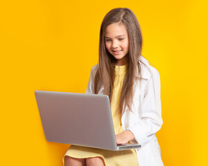 Naklejka premium A teenage girl with a laptop book. A beautiful European brunette girl is sitting with a laptop, working, communicating, studying. Teenagers and gadgets, Internet. Chat online on a computer.