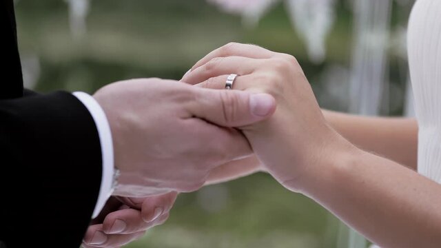 Bride putting wedding ring on brides finger close up summer day no face slow. luxury lifestyle. Bridal fashion.