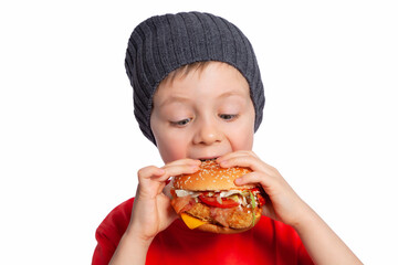 A child eats a chicken Burger. The boy takes a big bite of the Burger. A beautiful European boy is going to eat fast food. Happy child. A hamburger snack. Favorite children's food.