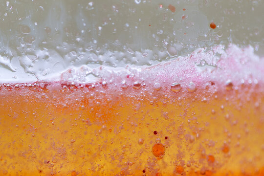 Macro photo of colourful children's experiment using oil, water, food colouring and fizzing tablet seen through clear glass