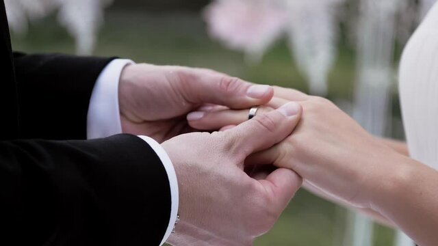 Groom putting wedding ring on brides finger close up summer day no face slow. luxury lifestyle. Bridal fashion.