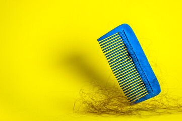 Hair loss concept. Broken hairs on plastic comb. Copy space.